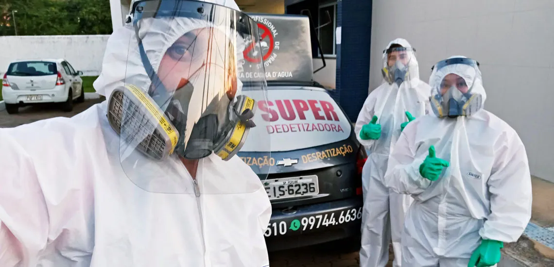 Equipe da Super Dedetizadora junto de veículos da empresa